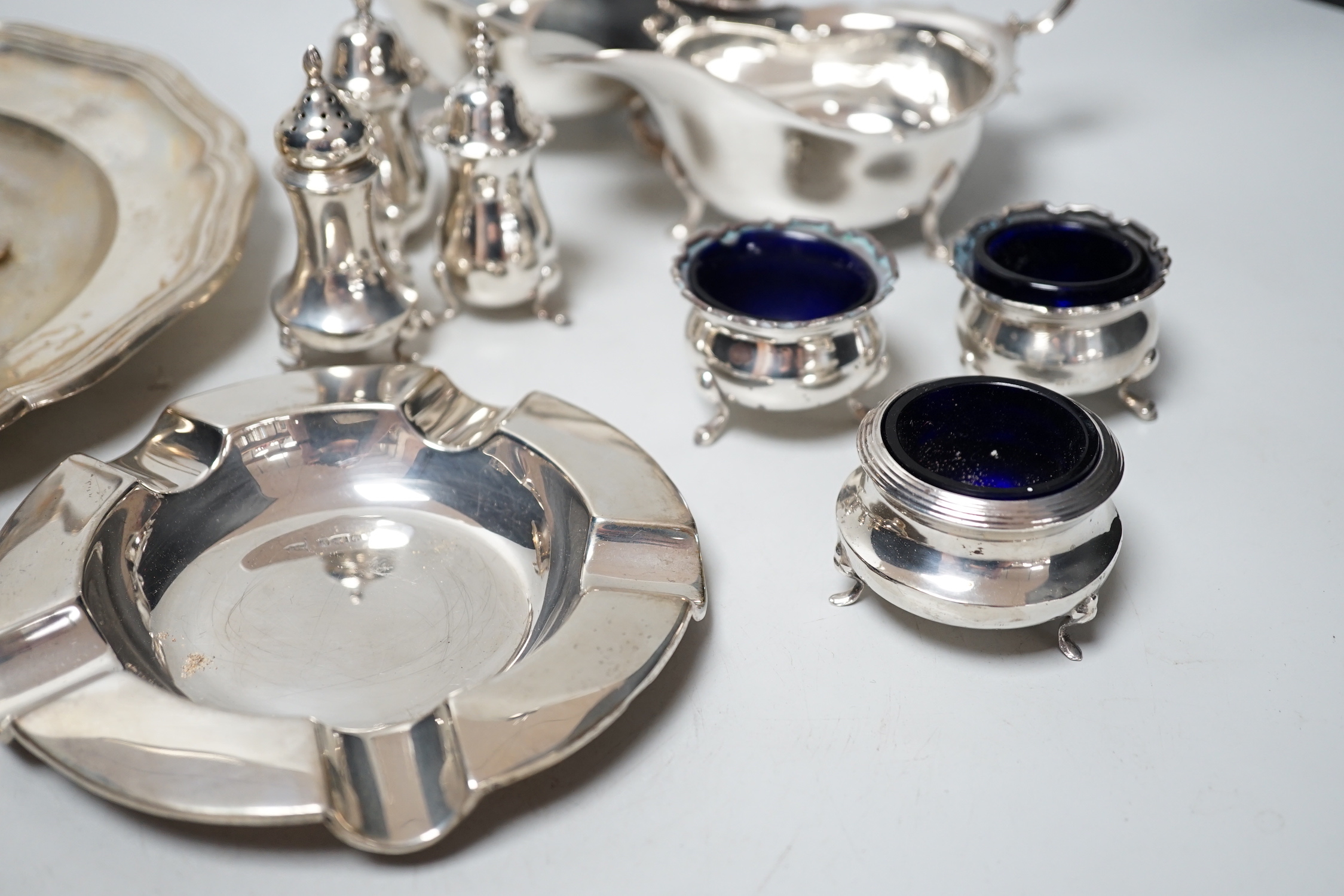 An 800 white metal plate, 24.8cm, a George V silver two handled bowl, a silver ashtray, six silver condiments, two 800 tots and minor plated ware, 24.1oz.